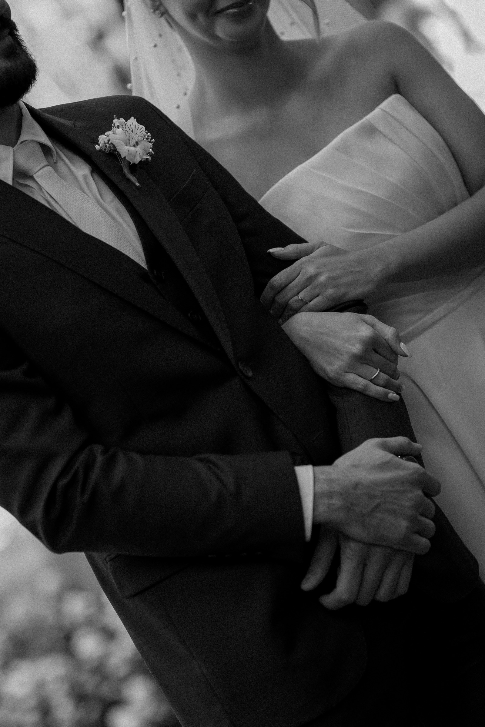 Detalhe das mãos dos noivos e do vestido, em preto e branco