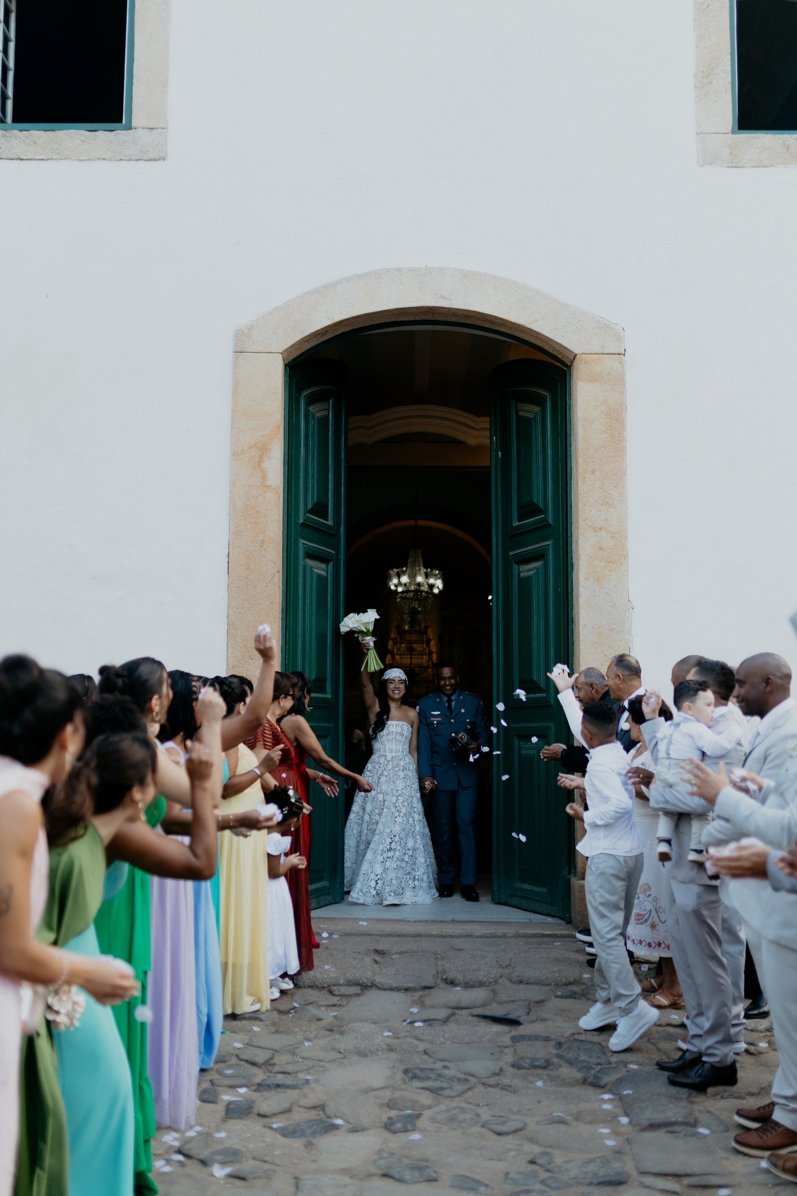 Convidados celebram a saída dos noivos na porta de uma igreja
